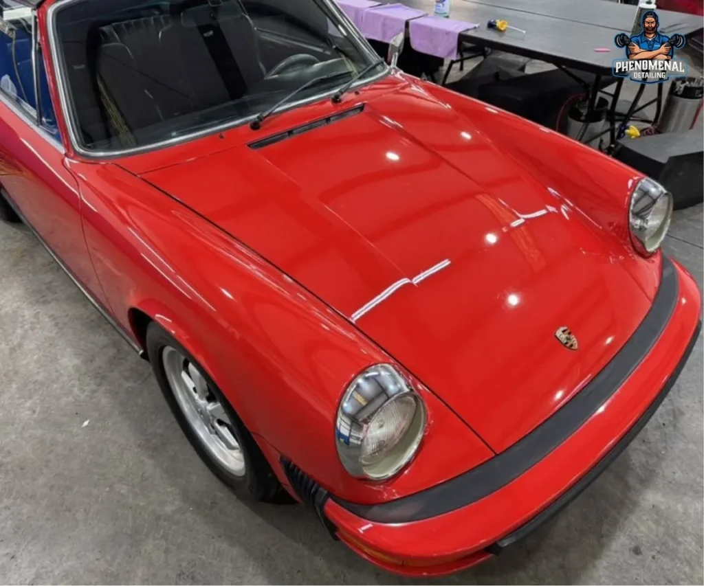 High-angle shot highlighting the glossy hood and round headlights of a vintage red Porsche.