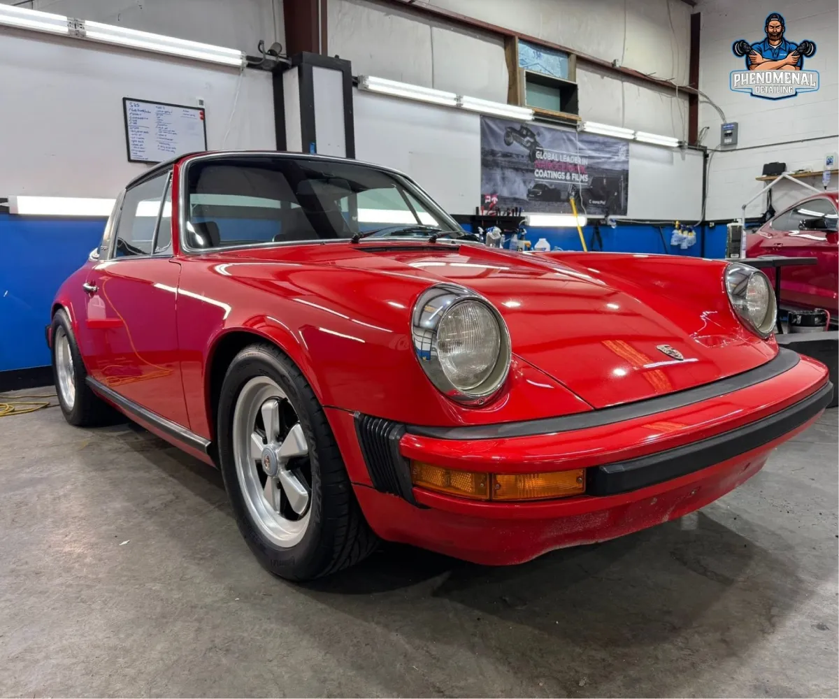 Front view of a classic red Porsche 911 Targa parked inside an auto shop bay.